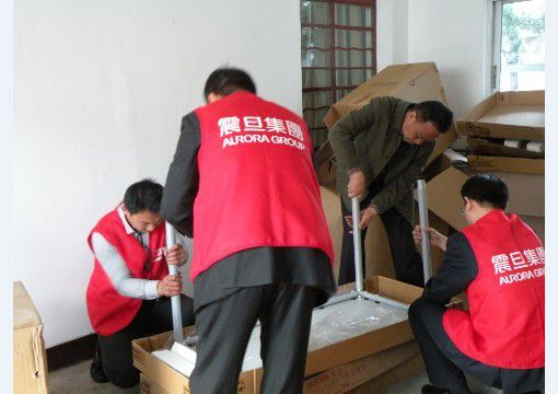 行銷組李家暉總監(jiān)(右一)、家具上海事業(yè)部閘北責(zé)任中心楊侃經(jīng)理(左二)、崇明縣新河鎮(zhèn)民政辦秦衛(wèi)明主任(右二)一起動(dòng)手參與組裝辦公桌，大家熱情高漲