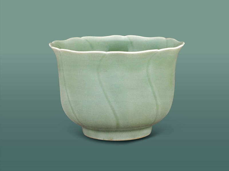 明宣德．仿龍泉青瓷葵口仰鐘式碗+模仿龍泉窯青釉，因?yàn)橛悦媪鲃?dòng)，口沿露白，陰刻S紋略顯深暗，色澤青翠素雅。（圖一）+圖片來源：《明代宣德官窯菁華特展圖錄》，頁175。